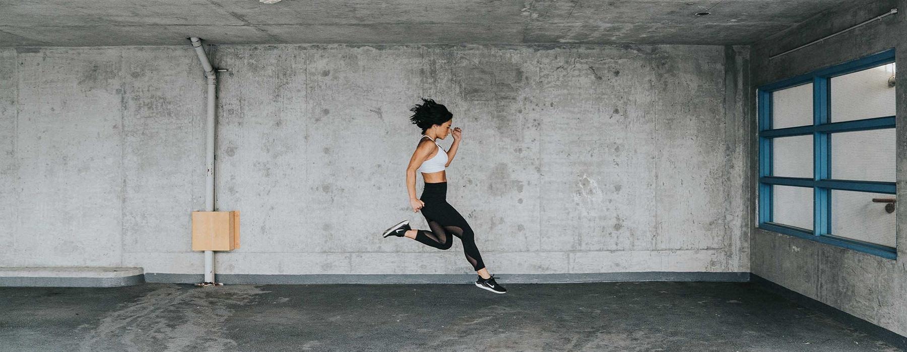 a woman jumping in a concrete room