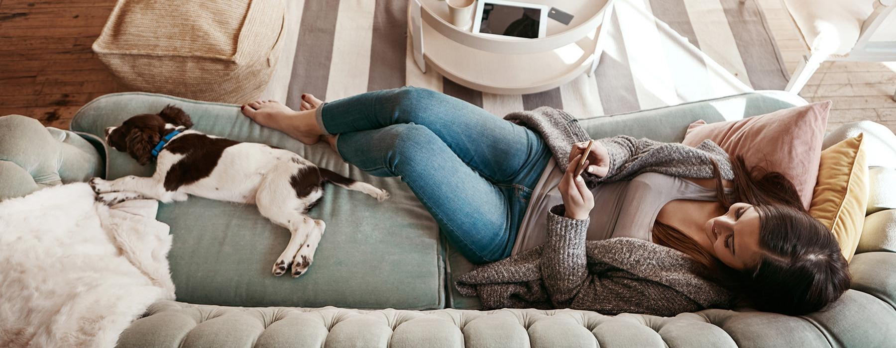a person lying on a couch with a dog