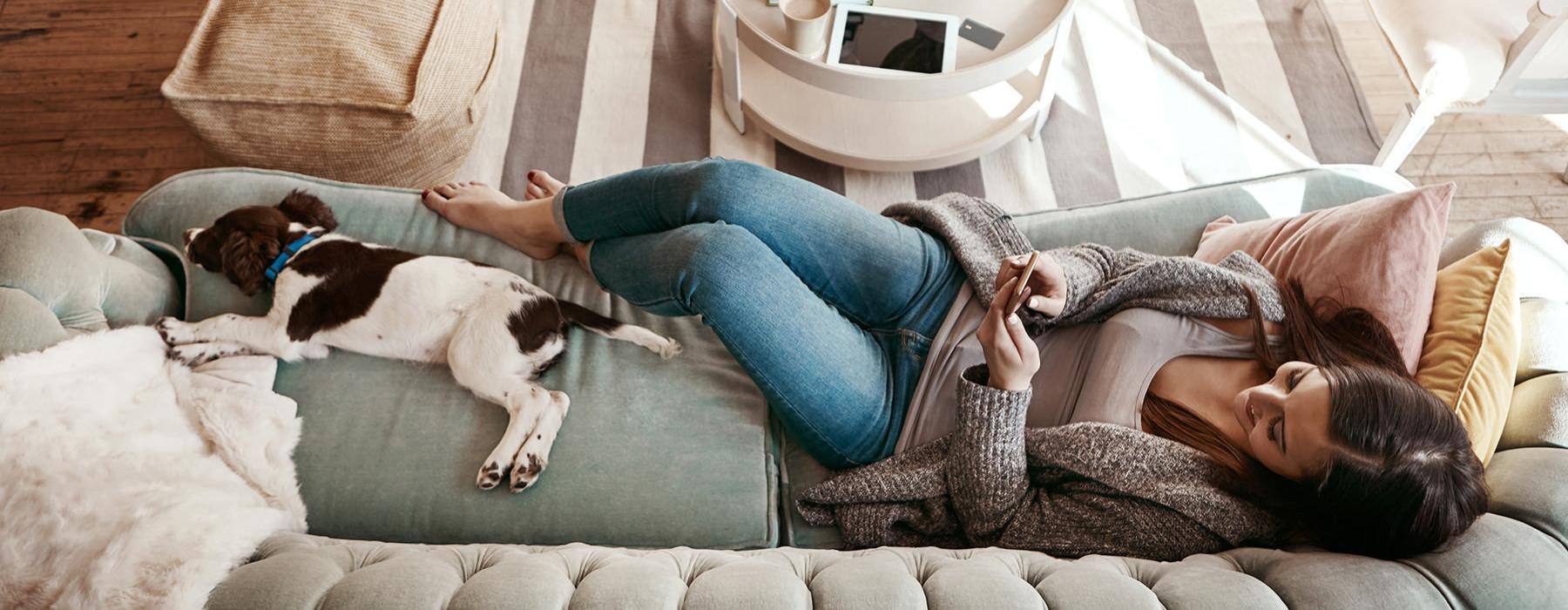 a person lying on a couch with a dog